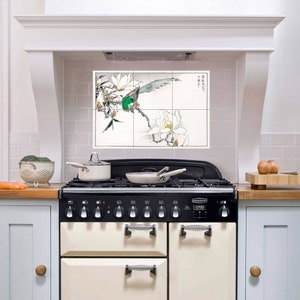 May include: A white kitchen with a cream-coloured range with black accents and a black top. The range has a digital clock that reads 07:30. Above the range is a white tile backsplash with a black and green bird and white flowers. The backsplash is made up of four tiles.