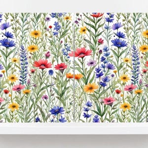 以下が含まれることがあります： 色とりどりの野草が描かれた水彩画のフローラルデザイン。赤いポピー、青いヤグルマギク、黄色いヒナギク、紫のラベンダーなど、白い背景に様々な花が描かれています。