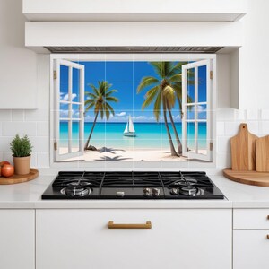 Puede incluir: Un azulejo de salpicadero de cocina con una escena de playa tropical. La imagen muestra un cielo azul brillante, agua turquesa, arena blanca, palmeras y un velero. La escena está enmarcada por una ventana blanca con contraventanas abiertas.