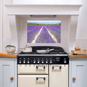 Puede incluir: Una cocina blanca con un salpicadero de azulejos con un campo de lavanda detrás de una cocina negra y blanca con un horno de color crema. La cocina tiene seis quemadores y una pantalla digital de reloj.