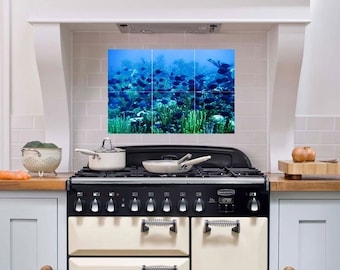 May include: A white kitchen range with a black top and black knobs. The range has a cream-colored oven door with spring-loaded handles. A colorful underwater scene with fish and coral is displayed on the backsplash.
