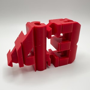 May include: A red 3D printed model of the number "423".