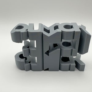 Può includere: Una scultura in 3D stampata in grigio della parola "remarkable". Le lettere sono impilate l'una sull'altra e sono leggermente sfalsate.