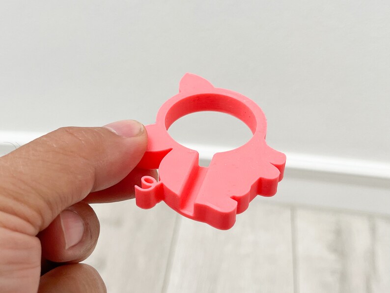 May include: A pink plastic pig-shaped phone holder. The holder has a hole in the middle for a phone to be placed.