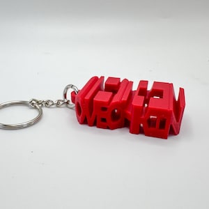 Könnte beinhalten: Roter Plastik-Schlüsselanhänger mit dem Wort "OVERKILL" in 3D-Buchstaben.