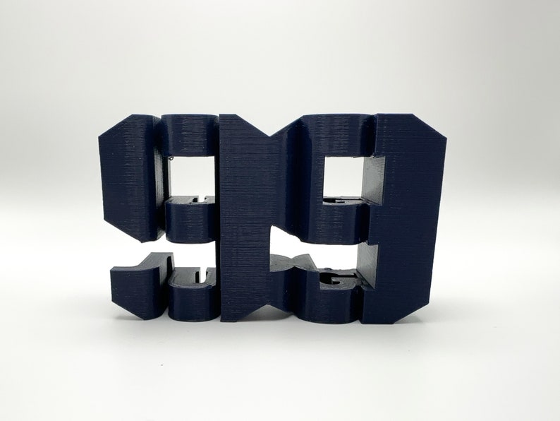 以下が含まれることがあります： 濃い青色のプラスチックで3Dプリントされた数字「99」。数字はユニークなレイヤー状のスタイルでデザインされています。