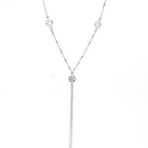 May include: A silver necklace with a dangling chain and three small round clear stones.