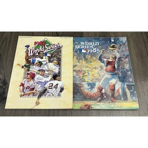 May include: Two vintage World Series baseball programs. The 1987 program features a collage of players and the text "1987 World Series." The 1985 program shows a catcher reaching for a ball, with the text "World Series 1985."