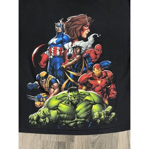 May include: Black t-shirt with a graphic print of various Marvel superheroes, including Captain America, Wolverine, Hulk, Iron Man, Storm, and Spider-Man.