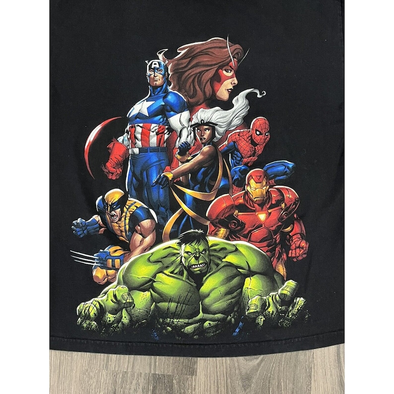 May include: Black t-shirt with a graphic print of various Marvel superheroes, including Captain America, Wolverine, Hulk, Iron Man, Storm, and Spider-Man.