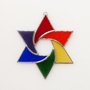 Pu&ograve; includere: Un ornamento a forma di Stella di David in vetro colorato con un design arcobaleno. La stella &egrave; composta da sei punte ed &egrave; decorata con vetro rosso, arancione, giallo, verde, blu e viola.