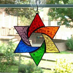 Pu&ograve; includere: Una stella di David in vetro colorato con un design arcobaleno. La stella &egrave; composta da sei punte ed &egrave; colorata in tonalit&agrave; di rosso, arancione, giallo, verde, blu e viola.