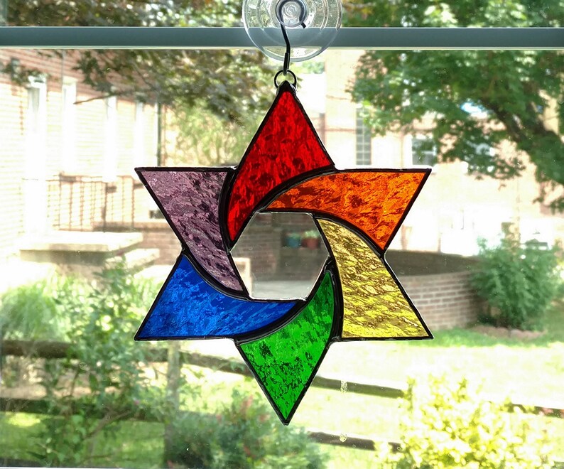 Pu&ograve; includere: Una stella di David in vetro colorato con un design arcobaleno. La stella &egrave; composta da sei punte ed &egrave; colorata in tonalit&agrave; di rosso, arancione, giallo, verde, blu e viola.