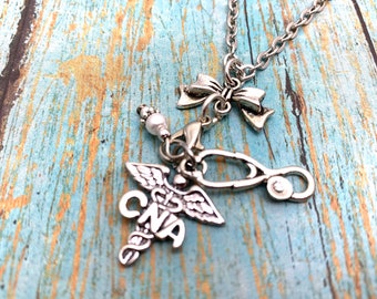 May include: Silver necklace with a charm featuring a caduceus with the letters CNA, a stethoscope, a pearl bead, and a silver bow.
