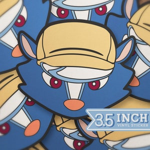 May include: A blue and yellow cartoon character with a yellow baseball cap. The character has red eyes and a white nose. The sticker is 3.5 inches wide. 3.5 INCH VINYL STICKER