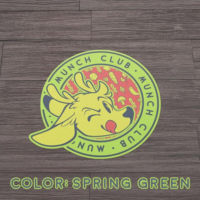 May include: A circular sticker with a cartoon deer head in the center, surrounded by the words "MUNCH CLUB" in a green circle. The deer is yellow with a red tongue. The background is red with vegetables. The text "COLOR: SPRING GREEN" is at the bottom.