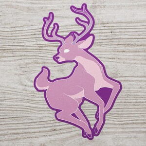 May include: A purple deer sticker with a pink body and white eyes. The deer has large antlers with a white starry pattern.