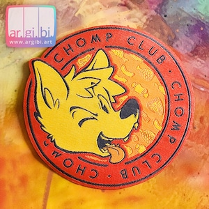 May include: A red and yellow embroidered patch with a cartoon wolf head and the text "CHOMP CLUB CHOMP CLUB" around the edge.