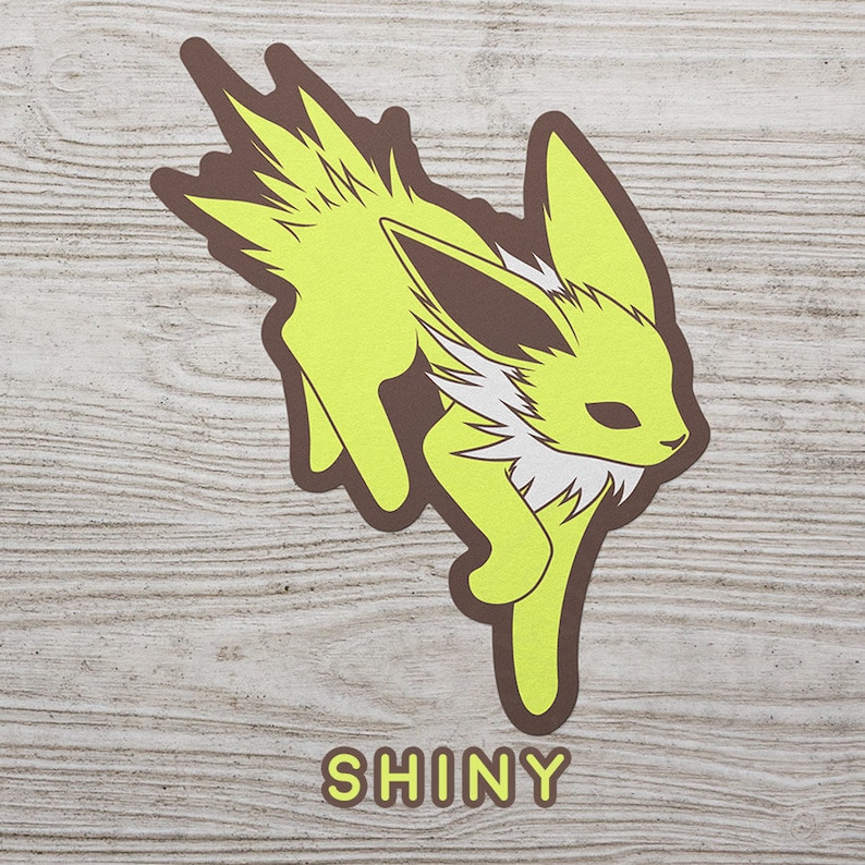 May include: A yellow and brown shiny Eevee Pokemon character illustration with the word "SHINY" printed below.
