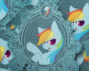 May include: A sticker featuring a light blue pony with a rainbow-colored mane and tail, enclosed in an ornate, dark teal filigree frame. The design includes a small rainbow cloud icon at the top and a repeating pattern of the same pony.