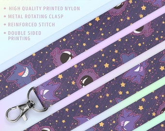May include: An 18-inch double-sided lanyard with a purple and black print of a ghost Pokemon character against a starry background. The lanyard features a metal rotating clasp and reinforced stitching.  PKMN GHOST TYPES.