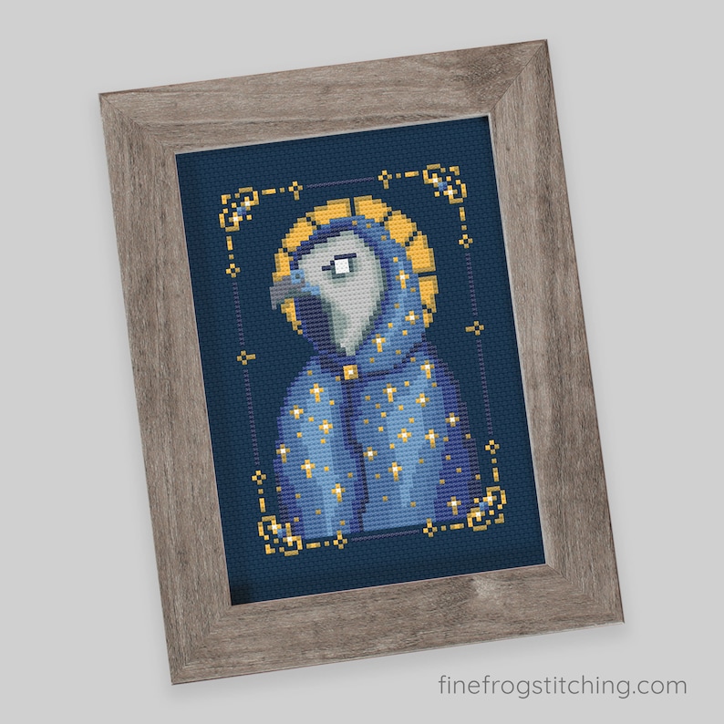 Pode incluir: Arte em ponto cruz de um p&aacute;ssaro vestindo uma t&uacute;nica azul com estrelas douradas e uma aur&eacute;ola dourada, emoldurada em uma moldura de madeira cinza. O p&aacute;ssaro tem uma cabe&ccedil;a cinza e um olho branco. O fundo &eacute; azul escuro. O site finefrogstitching.com &eacute; vis&iacute;vel.