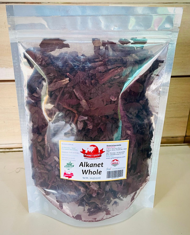 May include: A clear, resealable plastic pouch filled with dark brown, dried Alkanet root pieces. A white label on the front features the text Planet Spices, Alkanet Whole, and Net Wt.: 100 g (3.53 oz), along with a barcode and contact details.