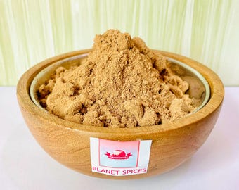 Puede incluir: Un bol de madera lleno de un montón de polvo de especias de color marrón claro. El bol tiene una etiqueta que dice "Planet Spices".