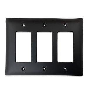 May include: Black wall plate with three rectangular openings for electrical outlets or switches.