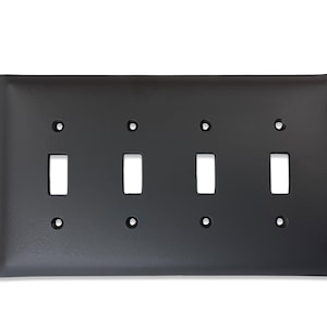 May include: A black metal 4-gang switch plate with four rectangular cutouts for toggle switches.