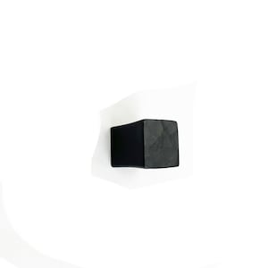 May include: Black square cabinet knob with a slightly rounded edge.