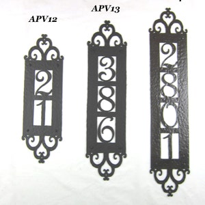 May include: Three black metal house number plaques with ornate scrollwork designs. The plaques are labeled APV12, APV13, and APV14. The numbers on the plaques are 21, 386, and 2801.