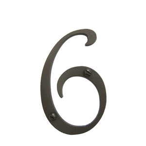 May include: A black metal house number six with a decorative, stylized font. The number is attached to a surface with two visible screws.