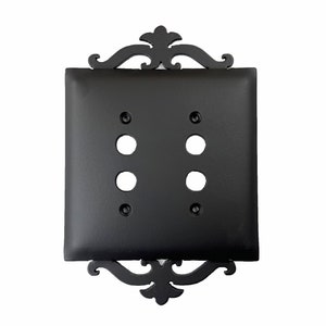 May include: Black double switch plate with an ornate, decorative, black metal frame.