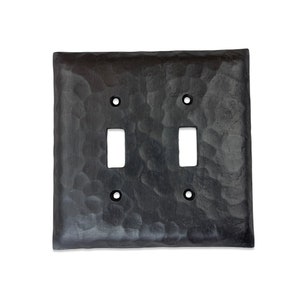 May include: Black metal double toggle light switch cover with a hammered finish.