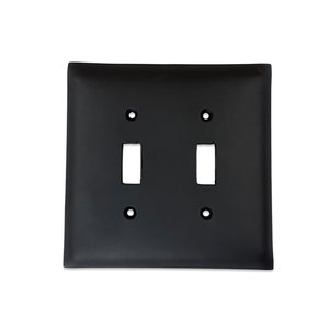 May include: Black double toggle light switch plate cover. The plate has a matte finish and is designed to fit standard toggle switches.