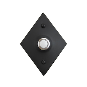 May include: A black diamond-shaped doorbell button with a round, white button in the center. The button has a silver trim around the edge.