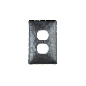May include: A black metal outlet cover with a hammered texture.