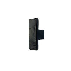 May include: Black ceramic cabinet knob with a rectangular shape and a slightly textured surface.