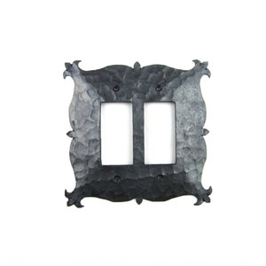 May include: A black metal double light switch cover with an ornate, hammered design and a slightly distressed finish.