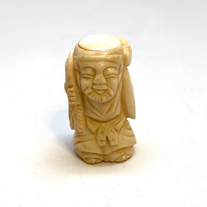 May include: A small, carved ivory figurine of a man wearing a traditional Japanese robe. The figurine is detailed and has a smooth, creamy white finish.
