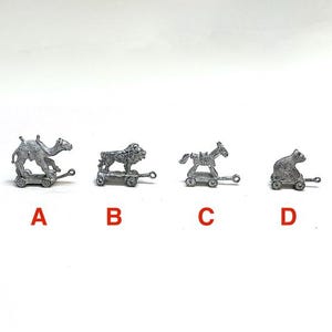May include: Four silver-toned metal animal figurines on small wheeled carts, labeled A, B, C, and D. The figures include a camel, a lion, a horse, and a cat, each mounted on a base with two wheels and a small loop at the front for attachment.