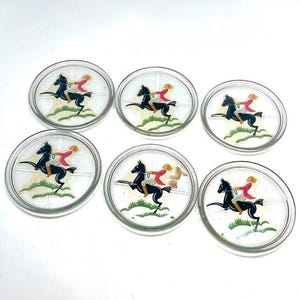 May include: Set of six clear glass coasters. Each coaster features a black horse with a rider in red and white attire. The design is set against a white background with green accents, creating a vintage aesthetic.