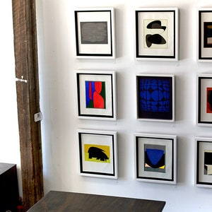 Puede incluir: Una pared de galer&iacute;a con nueve impresiones de arte abstracto enmarcadas. Las impresiones presentan formas geom&eacute;tricas y patrones en varios colores, incluidos el negro, el blanco, el rojo, el azul, el verde y el amarillo.