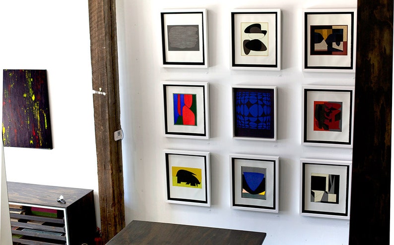 Puede incluir: Una pared de galer&iacute;a con nueve impresiones de arte abstracto enmarcadas. Las impresiones presentan formas geom&eacute;tricas y patrones en varios colores, incluidos el negro, el blanco, el rojo, el azul, el verde y el amarillo.