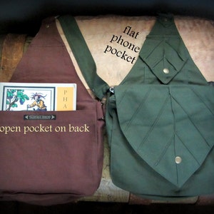 May include: Two canvas bags, one brown and one green. The brown bag has a large open pocket on the back and a smaller pocket on the front. The green bag has a large leaf-shaped pocket on the front with the text "flat phone pocket" written on the bag.