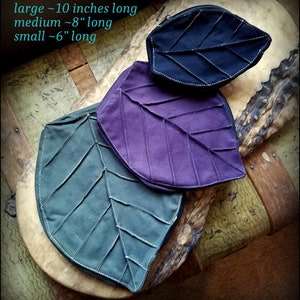May include: Three leaf-shaped zippered pouches in different sizes. The pouches are made of fabric and have a quilted design. The largest pouch is black, the medium pouch is purple, and the smallest pouch is green. The text "large ~10 inches long, medium ~8" long, small ~6" long" is visible in the image.