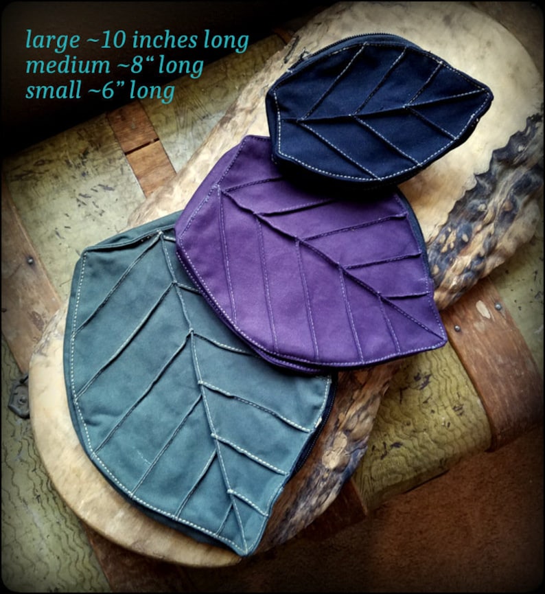 May include: Three leaf-shaped zippered pouches in different sizes. The pouches are made of fabric and have a quilted design. The largest pouch is black, the medium pouch is purple, and the smallest pouch is green. The text "large ~10 inches long, medium ~8" long, small ~6" long" is visible in the image.