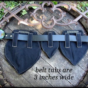May include: Black canvas belt tabs with white stitching, each measuring 3 inches wide. The tabs are attached to a black leather belt.