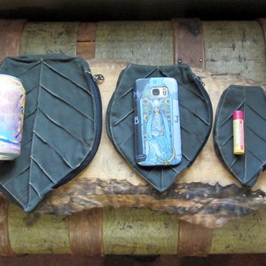 May include: Three green leaf-shaped zippered pouches of different sizes. The largest pouch is large enough to hold a can of sparkling water. The middle pouch is large enough to hold a smartphone. The smallest pouch is large enough to hold a lip balm.